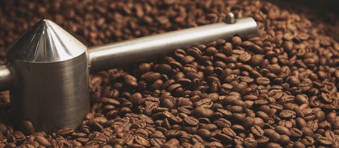 Dark, aromatic, chocolate coffee beans freshly baked and hot cool dawn inside the best professional roasting machine close up focus